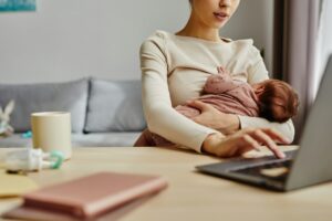 Young Mother Breastfeeding Using Laptop