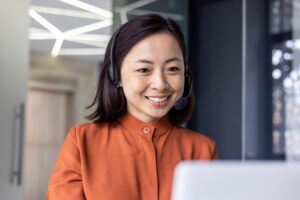 Close-up photo of young beautiful Asian woman talking on video call, looking at laptop web camera